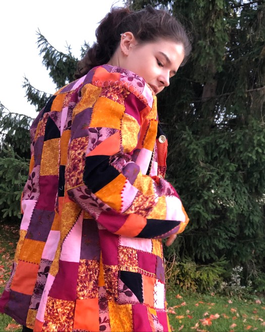 girl wearing crazy quilt jacket, tree backround
